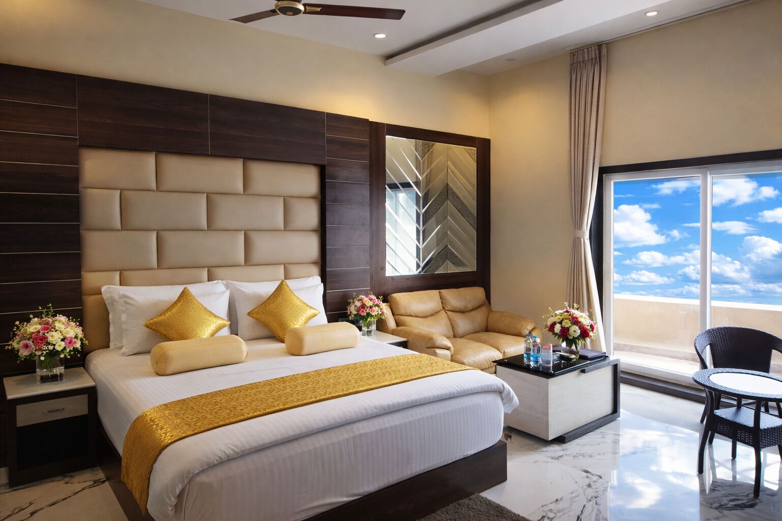Habitación de hotel con una cama grande, un sofá, una mesita de centro y vistas al cielo.