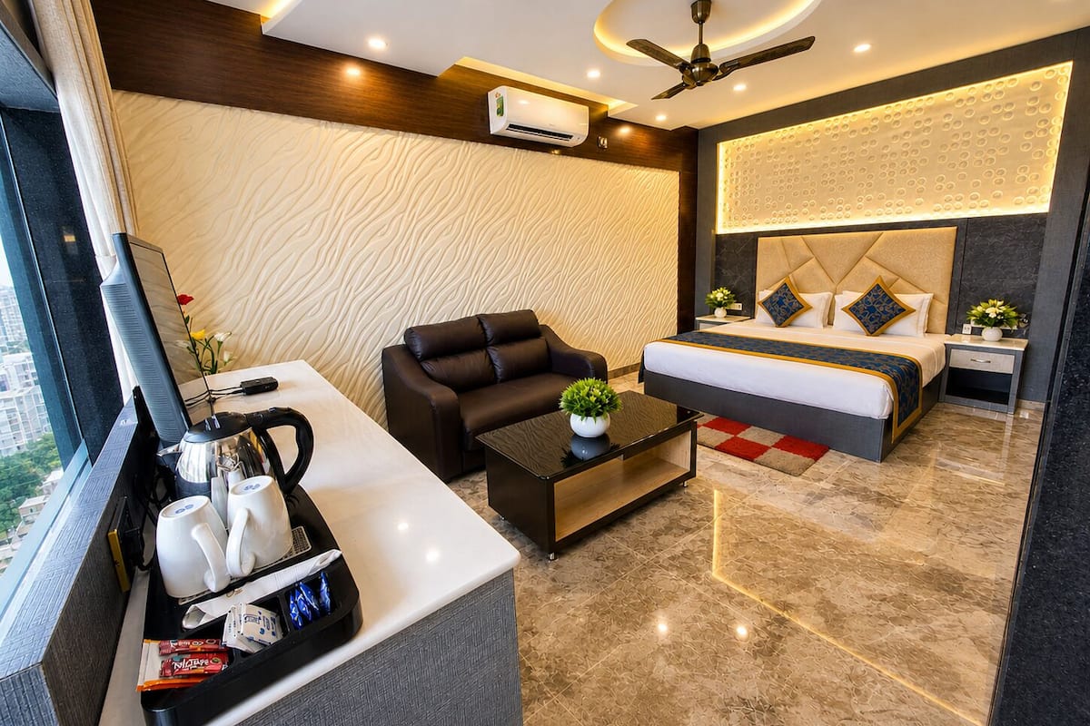 Una habitación de hotel moderna con cama, sofá, mesita de centro y escritorio con computadora y tazas de café.