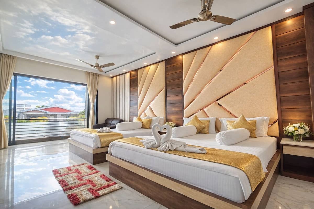 Una habitación de hotel moderna con una cama grande, dos mesitas de noche, un ventilador de techo y vistas al exterior.