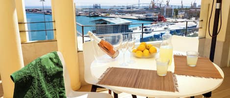 A balcony with a table set for two, featuring a bottle of champagne, glasses, lemons, and a glass of juice.