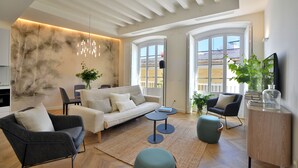 Un salon moderne avec un canapé, des fauteuils, une table basse et un téléviseur posé sur un meuble en bois.