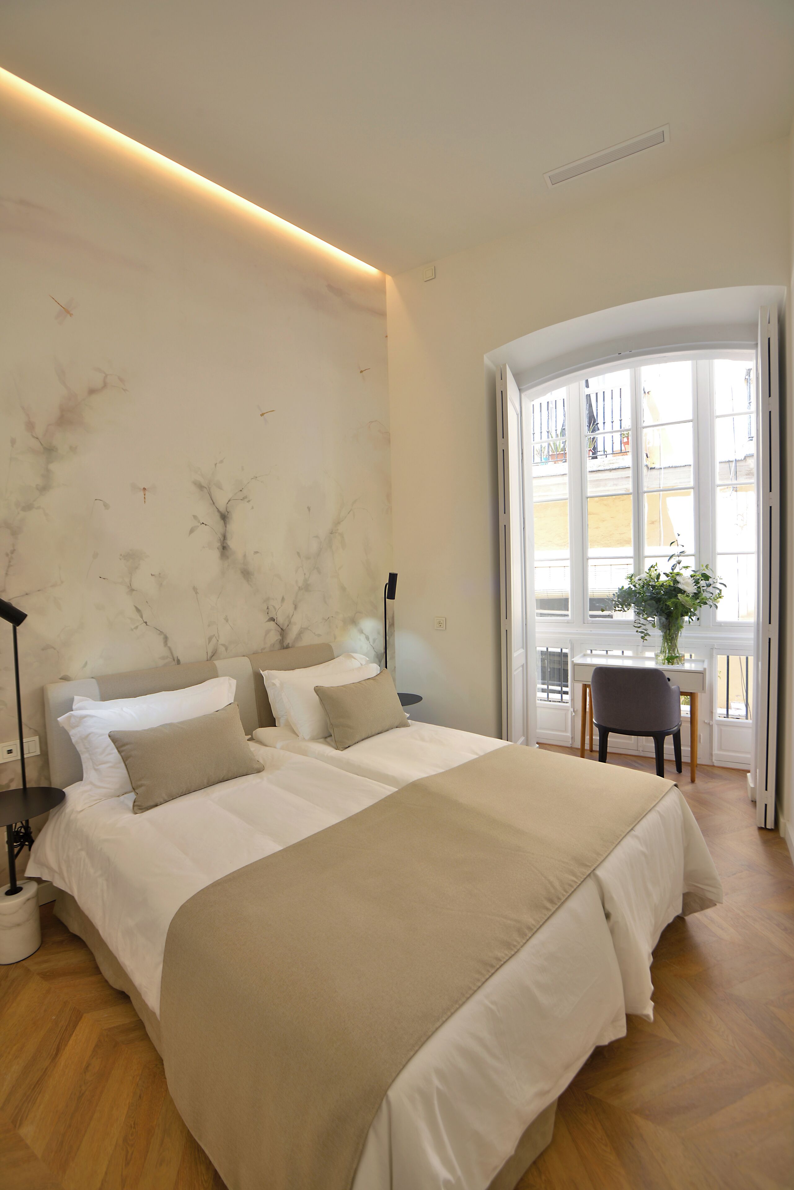 A bedroom with a large bed, a desk, and a chair near a window.