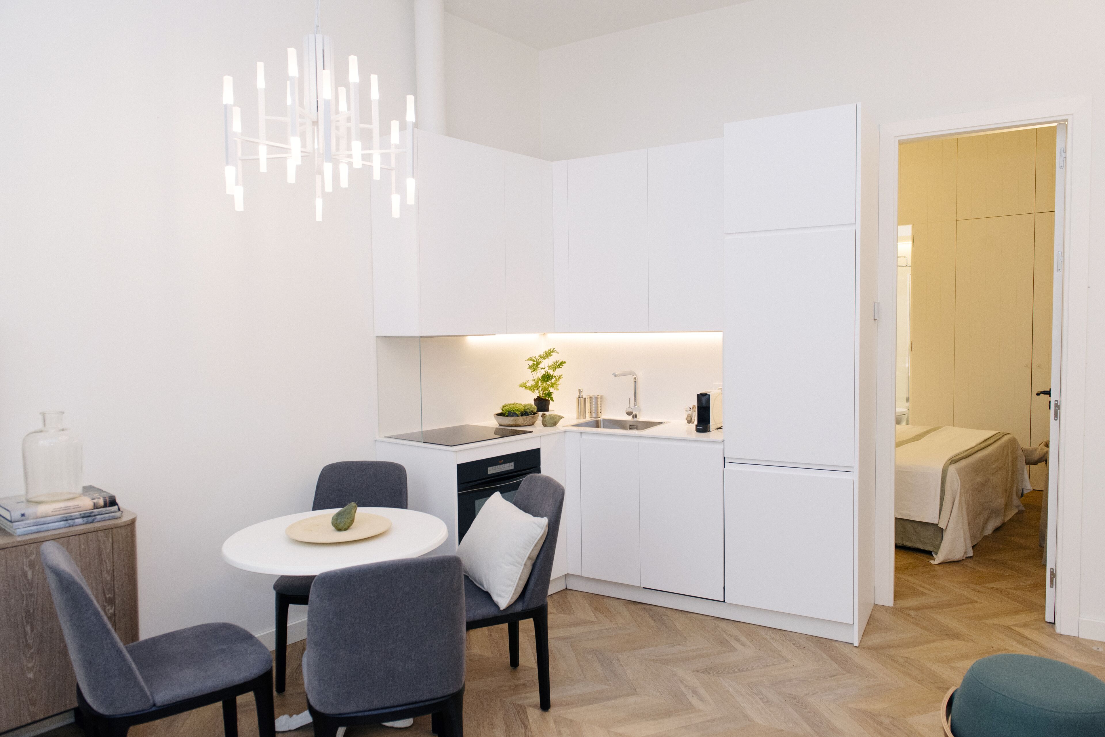 A compact kitchen with white cabinetry, a dining area with two chairs, and a small table.