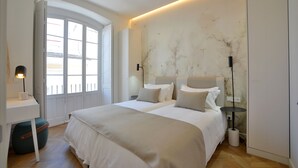 Une chambre moderne avec un grand lit, des tables de chevet, un bureau et une fenêtre.