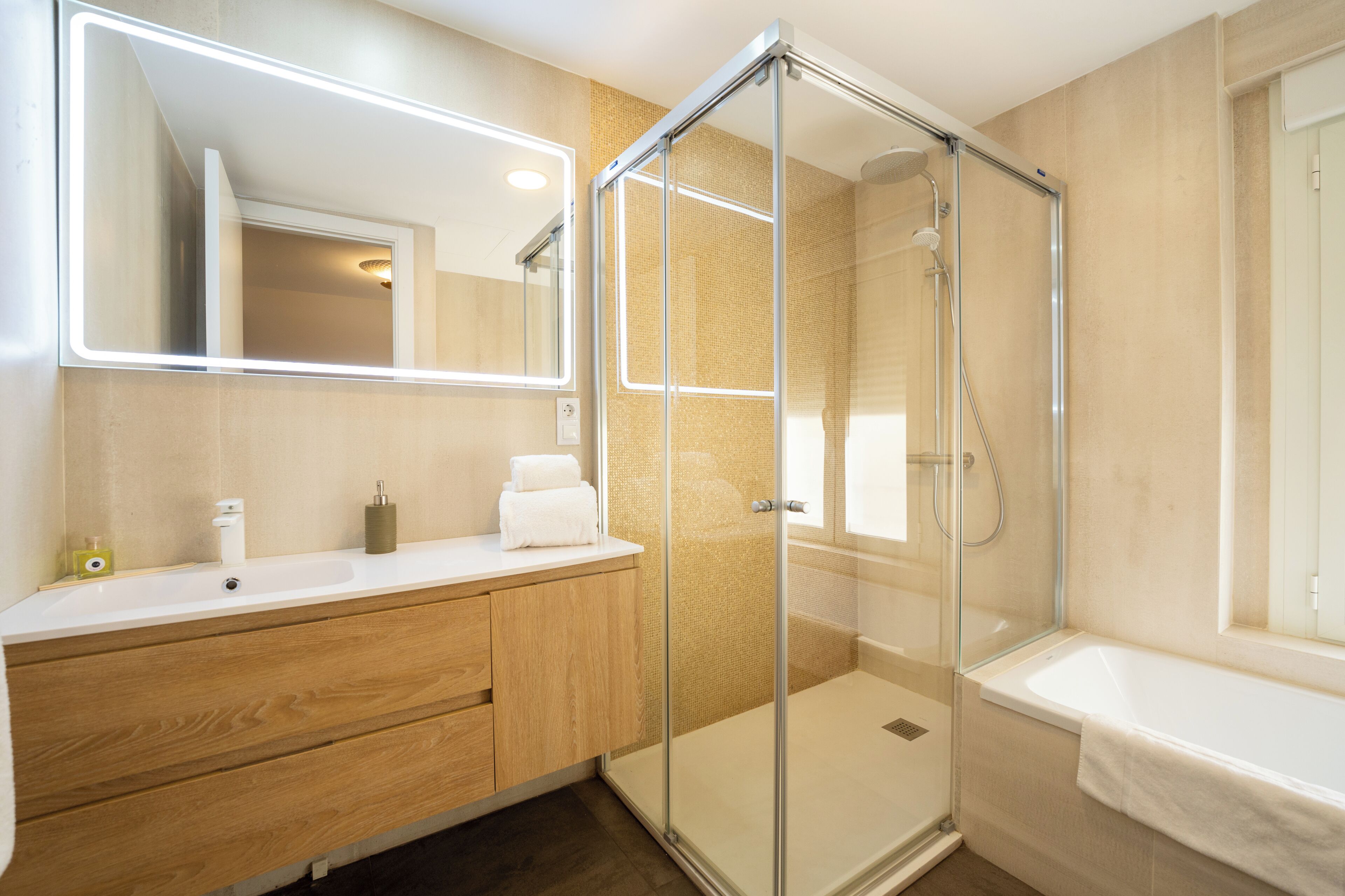 A modern bathroom with a glass-enclosed shower, a white sink, and a large mirror.