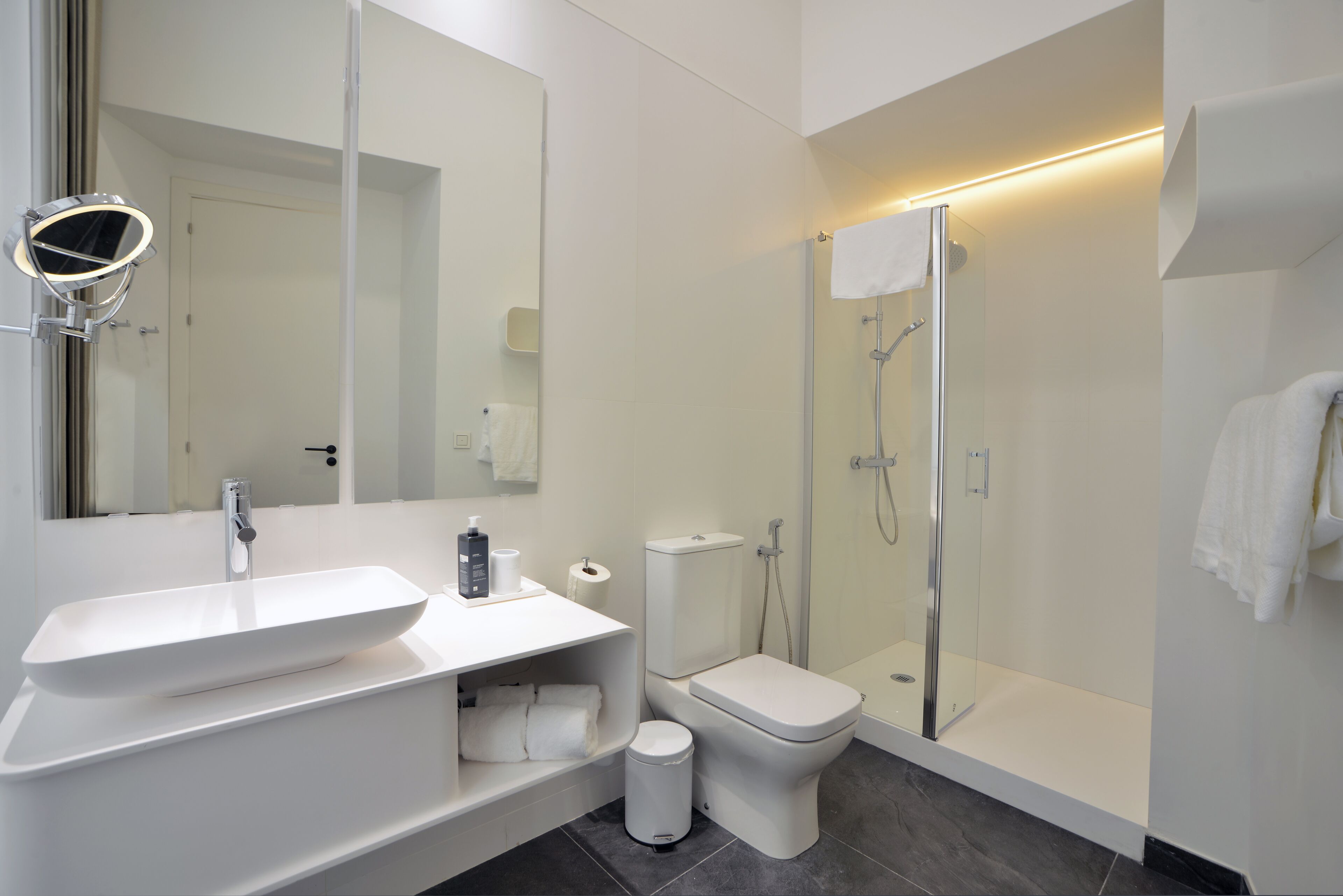 A modern bathroom with a white sink, toilet, and shower.