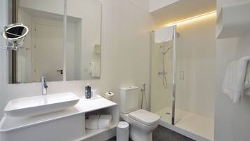 Un baño moderno con lavamanos, inodoro y ducha blancos.