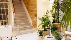 Un vaste espace intérieur doté d’un escalier menant à un niveau supérieur, agrémenté de plantes en pot et de meubles en osier.