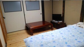 Un dormitorio con una cama, una mesita de noche de madera, una pequeña mesa y un armario con dos puertas.