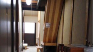 Una habitación de formato alargado y estrecho, con paredes de madera, un banco, una silla y una mesita.