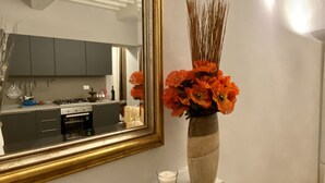 A modern kitchen with a large mirror, a vase with orange flowers, and a lit candle on the mantel. - sisters' home in the heart of Cortona (Cortona)