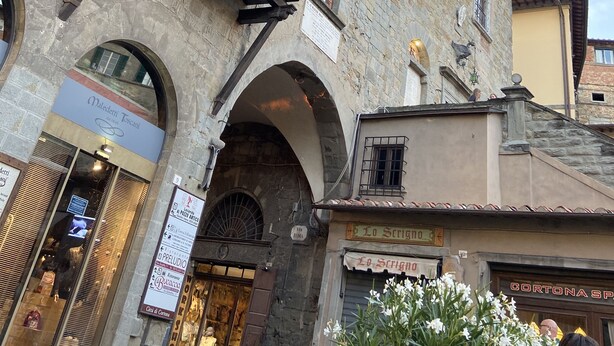 A historic stone building with a clock tower, arched windows, and a sign for 'Maledetti Toscani'. - sisters' home in the heart of Cortona (Cortona)