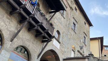 A historic stone building with a clock tower, arched windows, and a sign for 'Maledetti Toscani'.