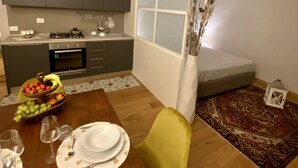 A modern kitchen with grey cabinets, a dining table set with plates and glasses, and a decorative vase with dried plants. - sisters' home in the heart of Cortona (Cortona)