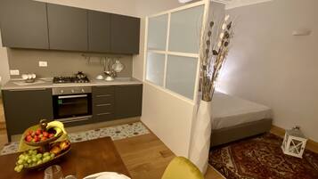 A modern kitchen with grey cabinets, a dining table set with plates and glasses, and a decorative vase with dried plants.