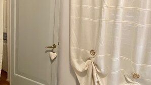 A room with a closed door, a hanging heart-shaped ornament, and a curtain with decorative buttons. - sisters' home in the heart of Cortona (Cortona)