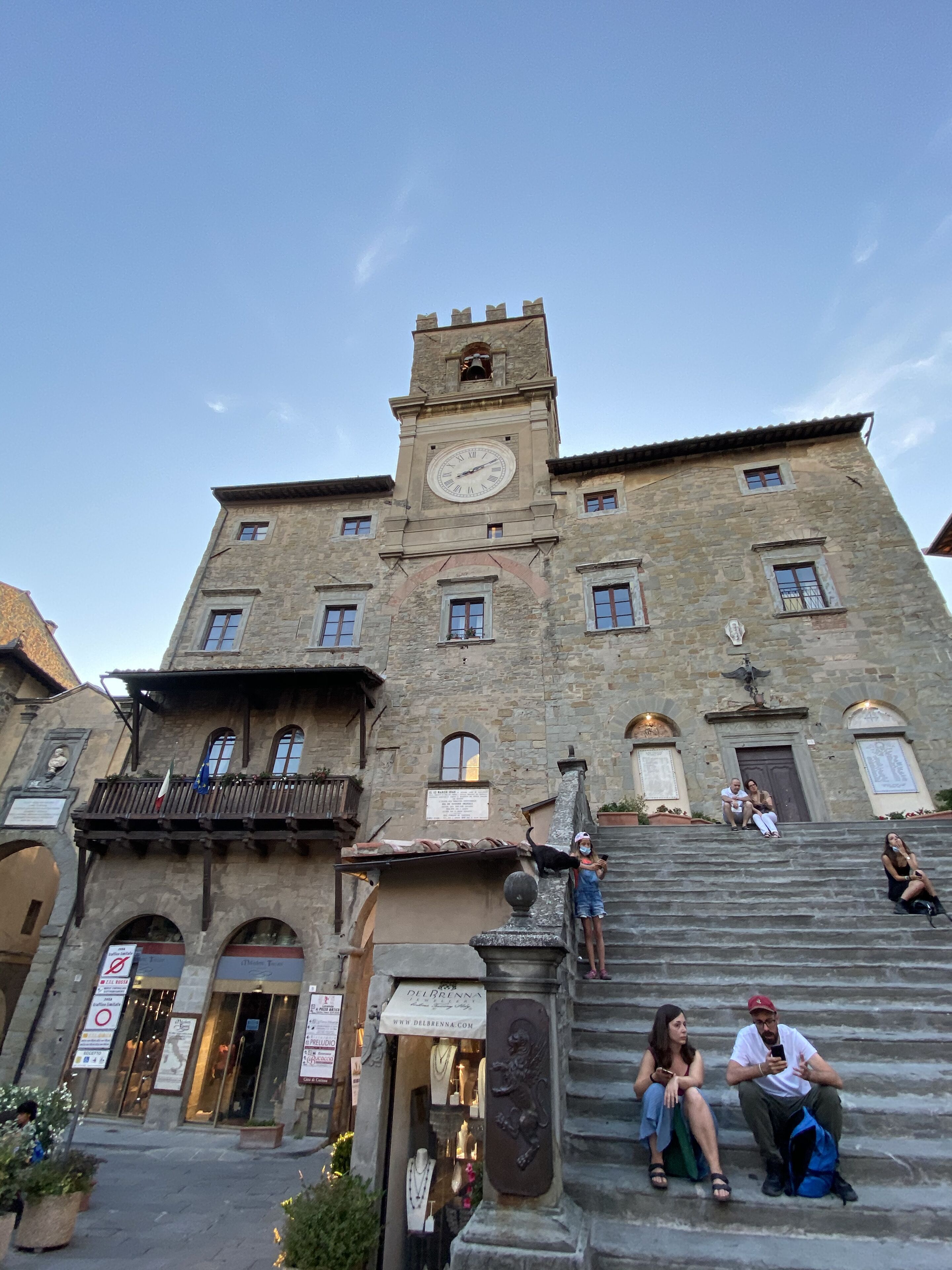 A historic building with a clock tower, stone facade, and a staircase leading to the entrance.