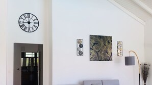 A spacious living room with a grey sectional sofa, a black coffee table, and a large wall clock. - Villa Samathan 3 bedrooms private pool 5mn from the beach (Saint-François)