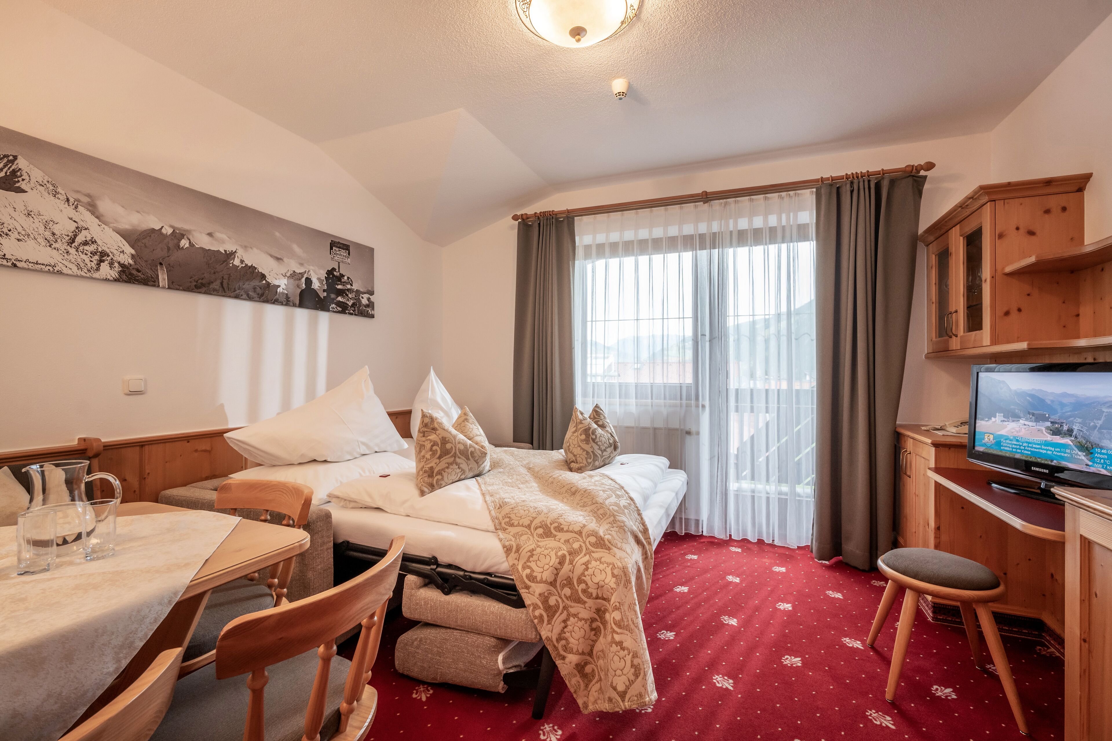 Een hotelkamer met een bed, een bureau, een televisie en een raam met gordijnen.