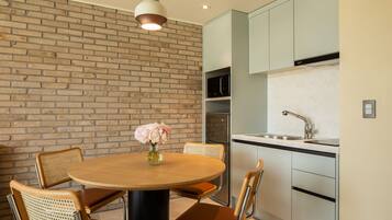 Una cocina moderna con pared de ladrillo, una mesa redonda de madera y cuatro sillas.