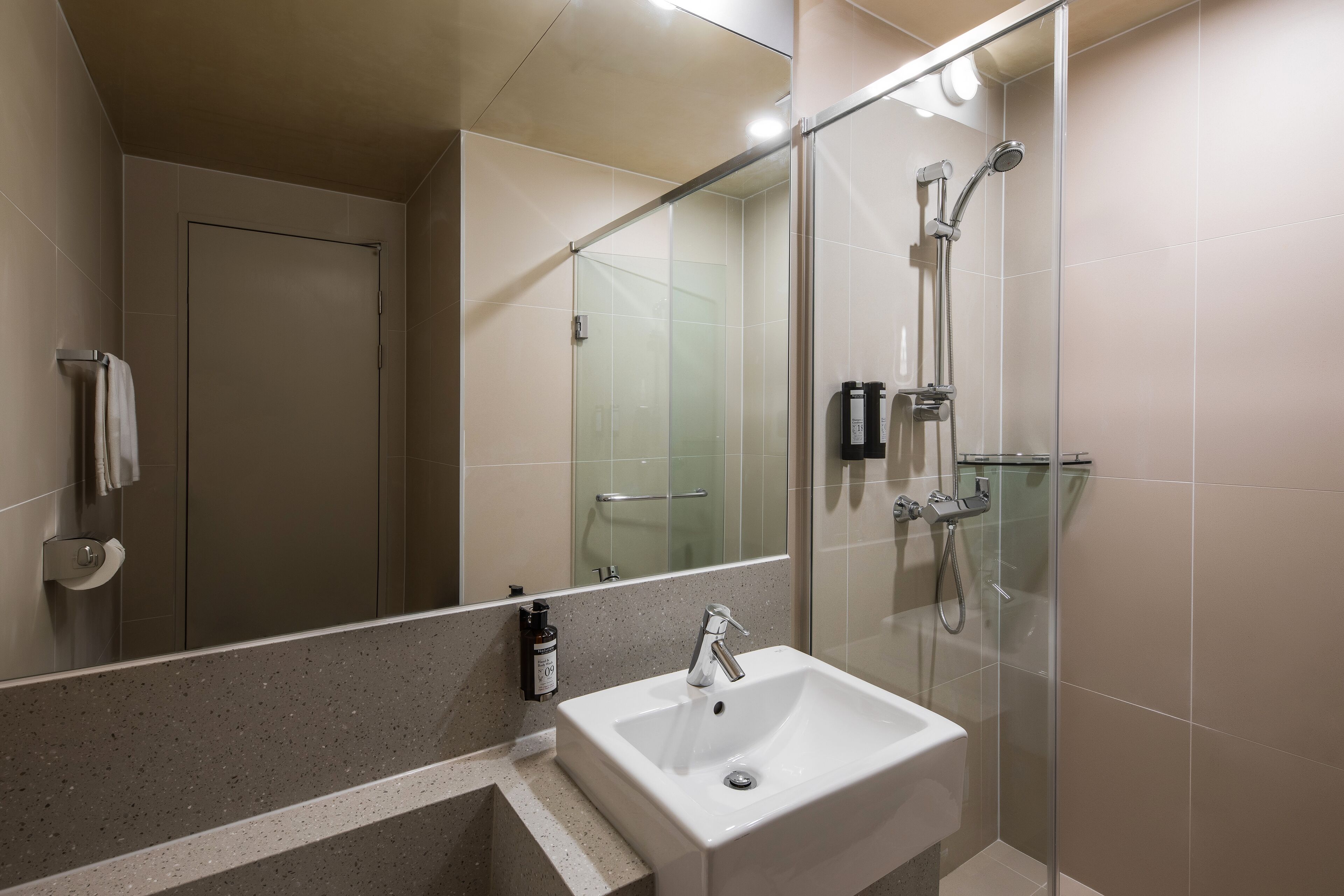 A modern bathroom with a glass-enclosed shower, a white sink, and a mirror above the sink.