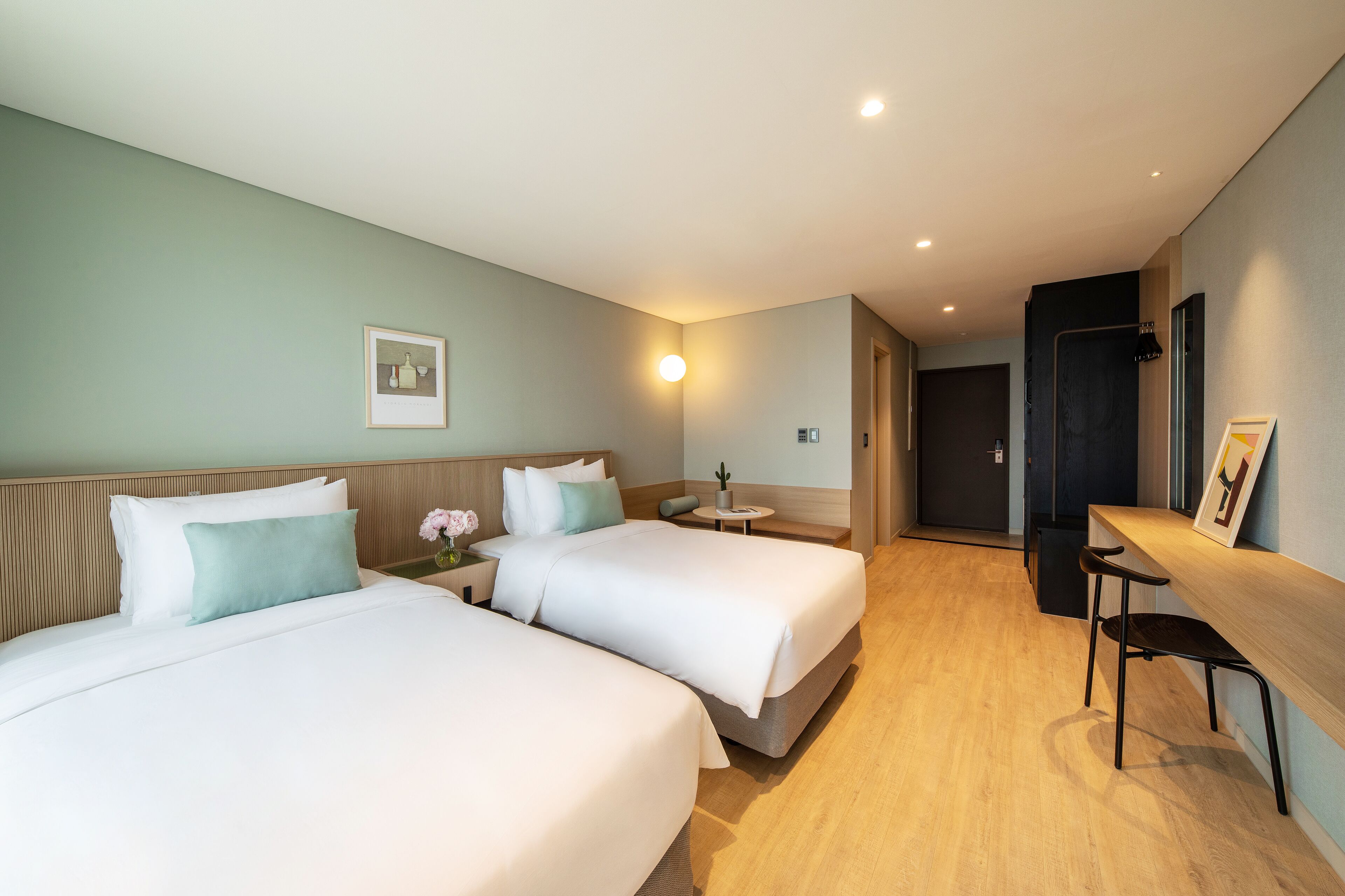 Habitación de hotel con dos camas, un escritorio y una silla.