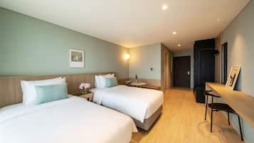 Habitación de hotel con dos camas, un escritorio y una silla.