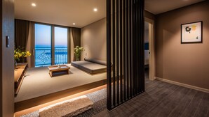 Habitación de hotel moderna con un amplio ventanal, zona de estar y vista al mar.