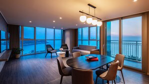 Una habitación de hotel moderna con un balcón grande, una mesa de comedor redonda y un sofá.