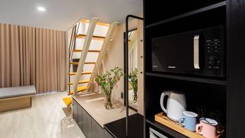 A modern kitchen with a microwave, kettle, and mugs on the counter.
