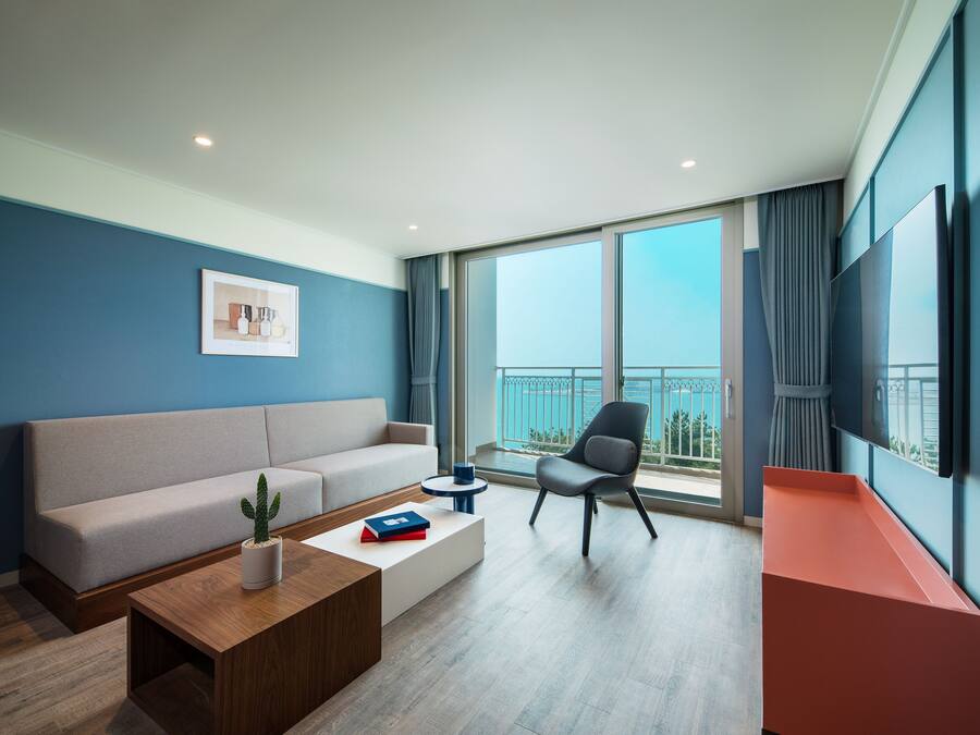 A modern living room with a sofa, a coffee table, a chair, and a TV mounted on the wall.