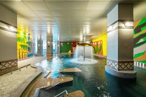 An indoor swimming pool with a water fountain, tiled walls, and a tiled floor.