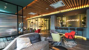 A modern lounge area with a sofa, chairs, and a bar with stools. - Ceylonz Suites by MyKey (Kuala Lumpur)