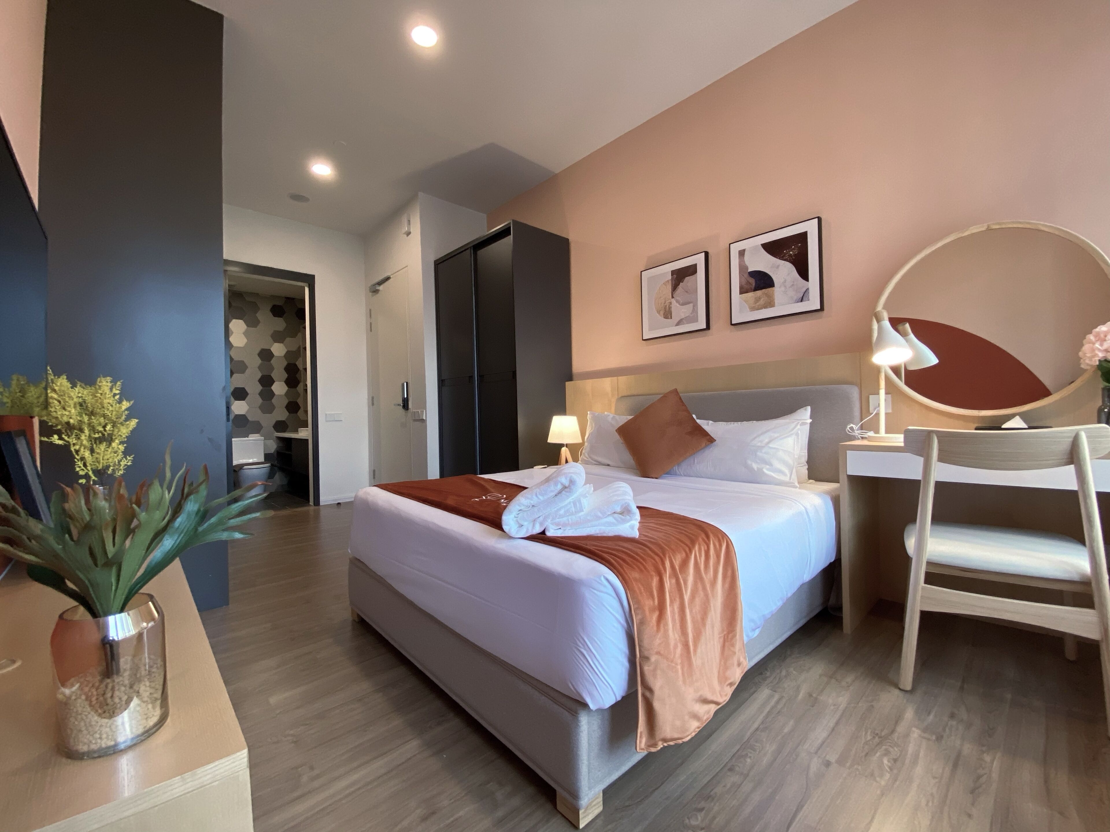 Una habitación de hotel moderna con una cama grande, una mesita de noche y un escritorio con una silla.