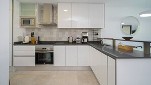 A modern kitchen with white cabinets, a microwave, a coffee maker, and a sink. - Apartamento Marion (Mar de Pulpi) (Almería)