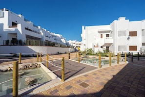 Un edificio moderno blanco con piscina y un sendero de ladrillos.