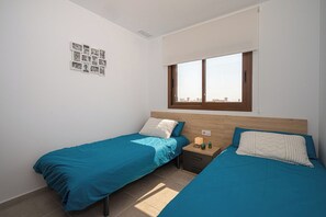 Une chambre avec deux lits, une table de chevet, une fenêtre et un collage de photos accroché au mur.
