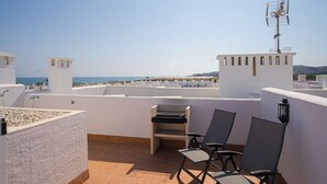 A rooftop terrace with a view of the sea, a barbecue grill, two chairs, and a satellite dish. - Apartamento Marion (Mar de Pulpi) (Almería)
