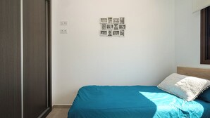 A bedroom with a bed, a wall-mounted photo collage, and a window. - Apartamento Marion (Mar de Pulpi) (Almería)