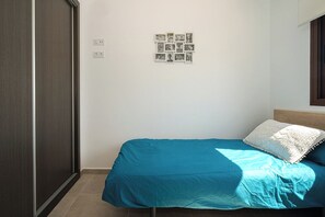 Een slaapkamer met een bed, een fotocollage aan de muur en een raam.
