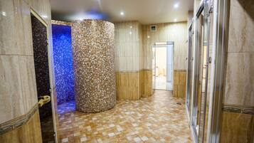 Bathroom features a checkered floor, mosaic-tiled column, and glass shower enclosure.