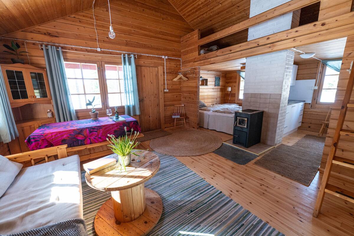Une cabane en bois comprenant un coin repas, une cuisine et un lit avec vue.