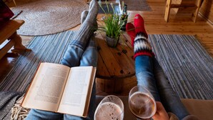 Interior acogedor de una cabaña con chimenea, un sofá, una mesita de centro y un libro.