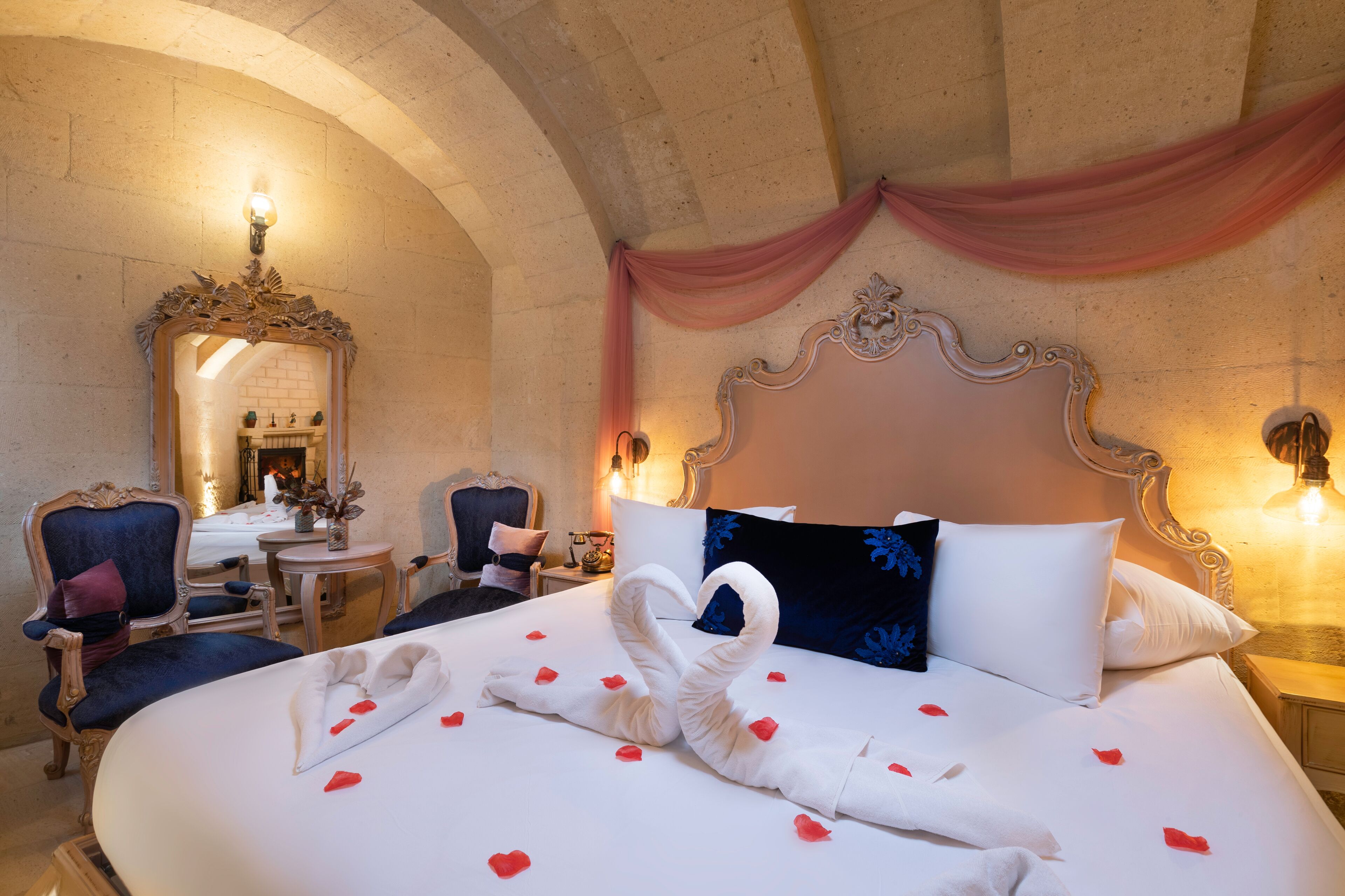 A hotel room with a large bed, a mirror, a desk, and a chair.