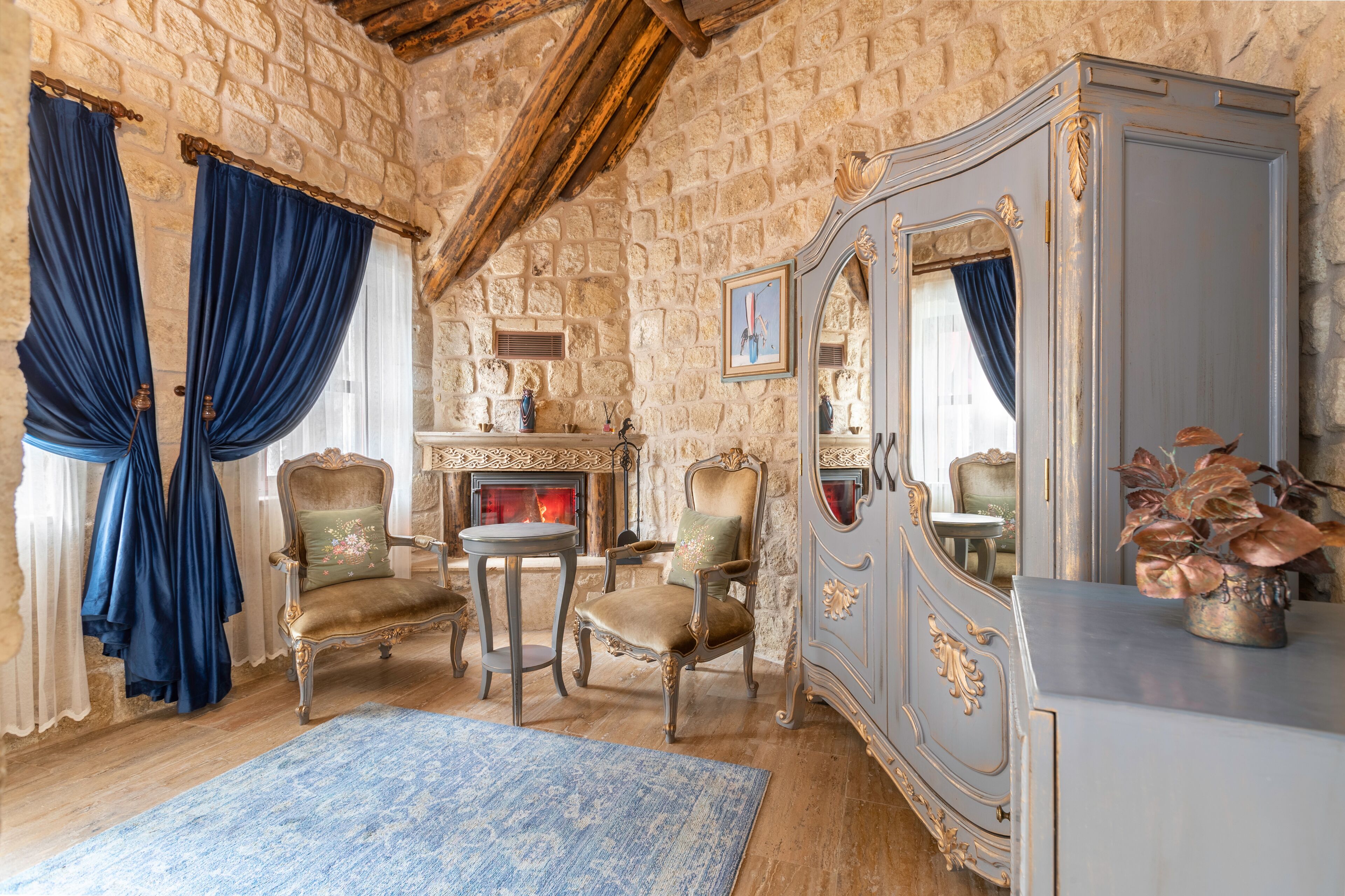 A room with stone walls, a fireplace, a mirror, and classic furniture.