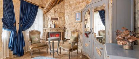 A room with stone walls, a fireplace, a mirror, and classic furniture.