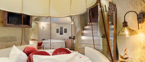 Un dormitorio con una cama grande, una lámpara colgante, un espejo y vistas a un baño y una escalera.