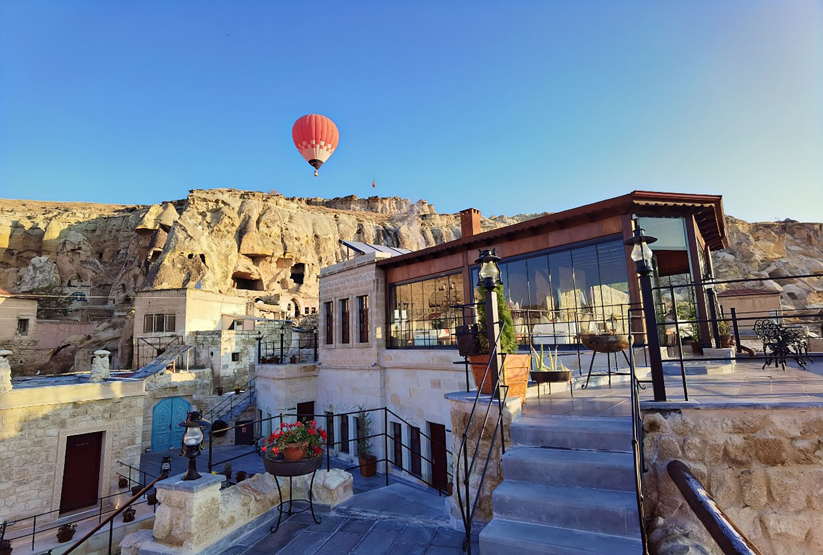 A hotel with a stone facade, a red hot air balloon in the background, and a staircase leading to the upper level.