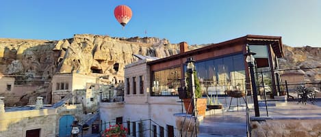 A hotel with a stone facade, a red hot air balloon in the background, and a staircase leading to the upper level.