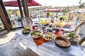 Una mesa servida con diversos platos y bebidas, con vistas a un paisaje pintoresco.